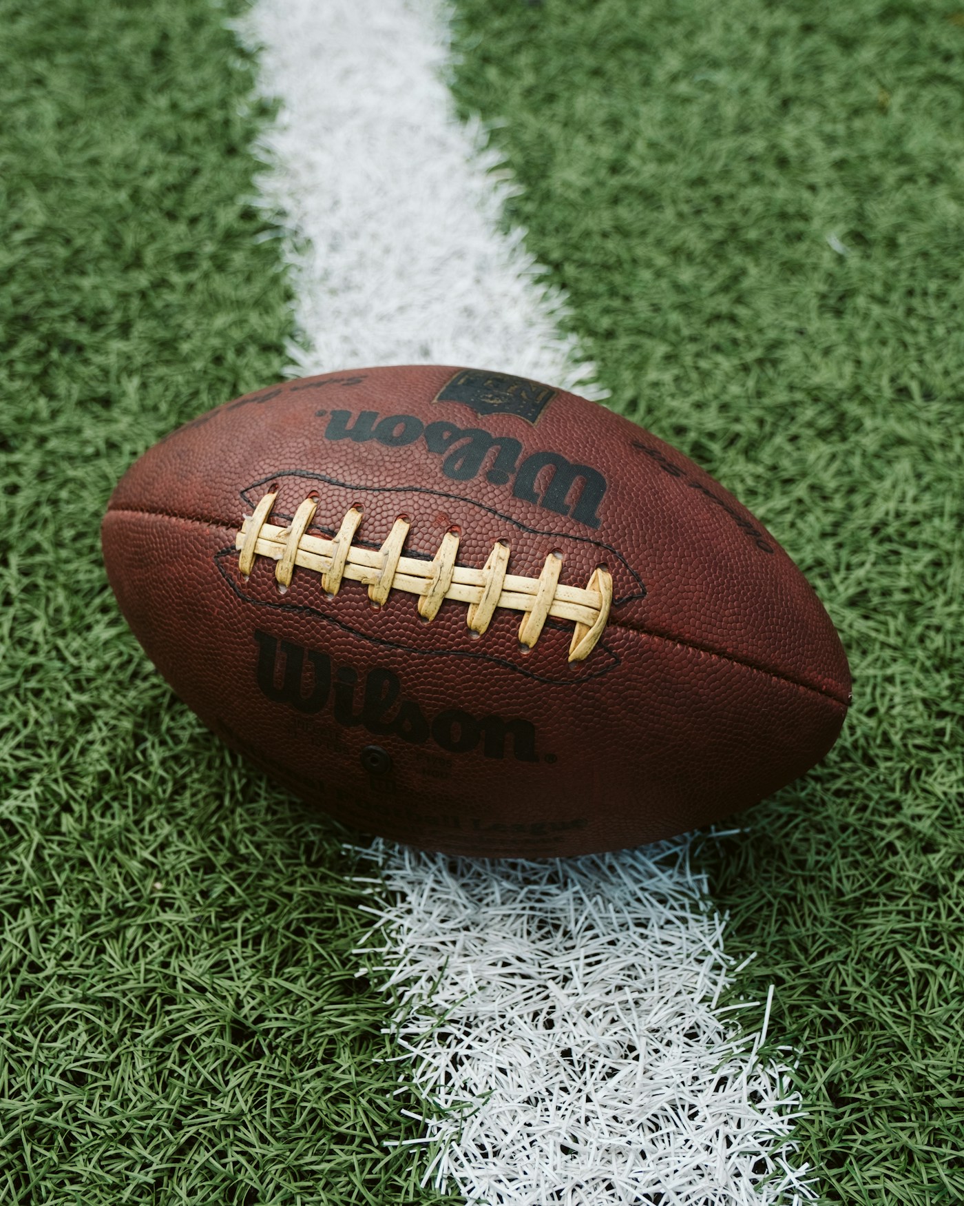 A worn football resting on a white yard line